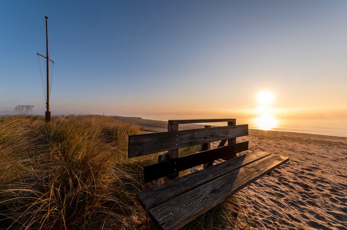 Strand mit Bank im Sonnenuntergang