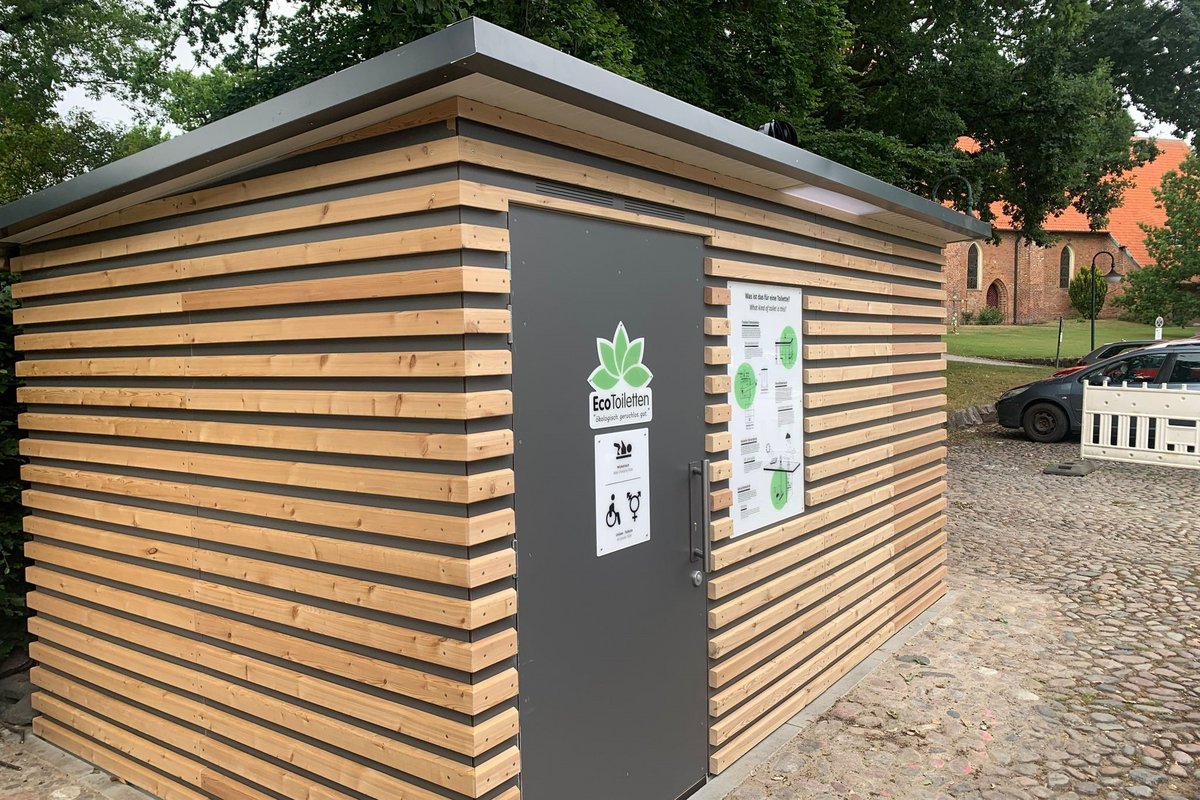 Toilettengebäude mit Holzverkleidung auf dem Kirchplatz Lensahn