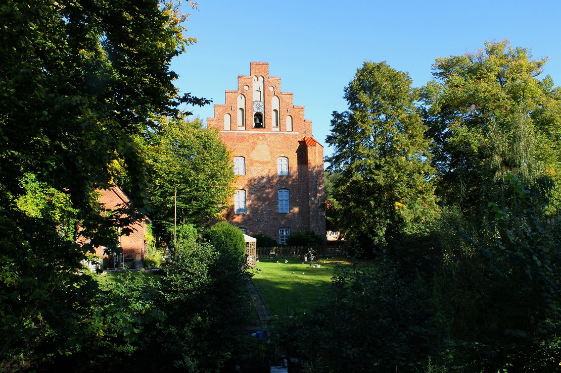 Rotes Backsteinkloster mit großen Bäumen davor