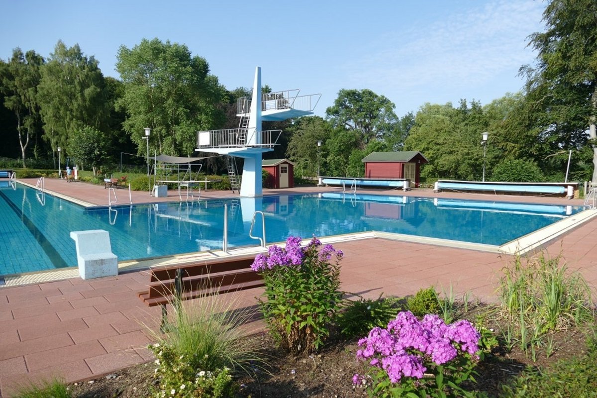 Ein Bild des Lensahner Waldschwimmbades mit Fokus das große Becken und den Sprungturm.