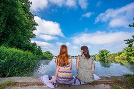Zwei Frauen sitzen am Steg mit Blick über den Mühlenteich