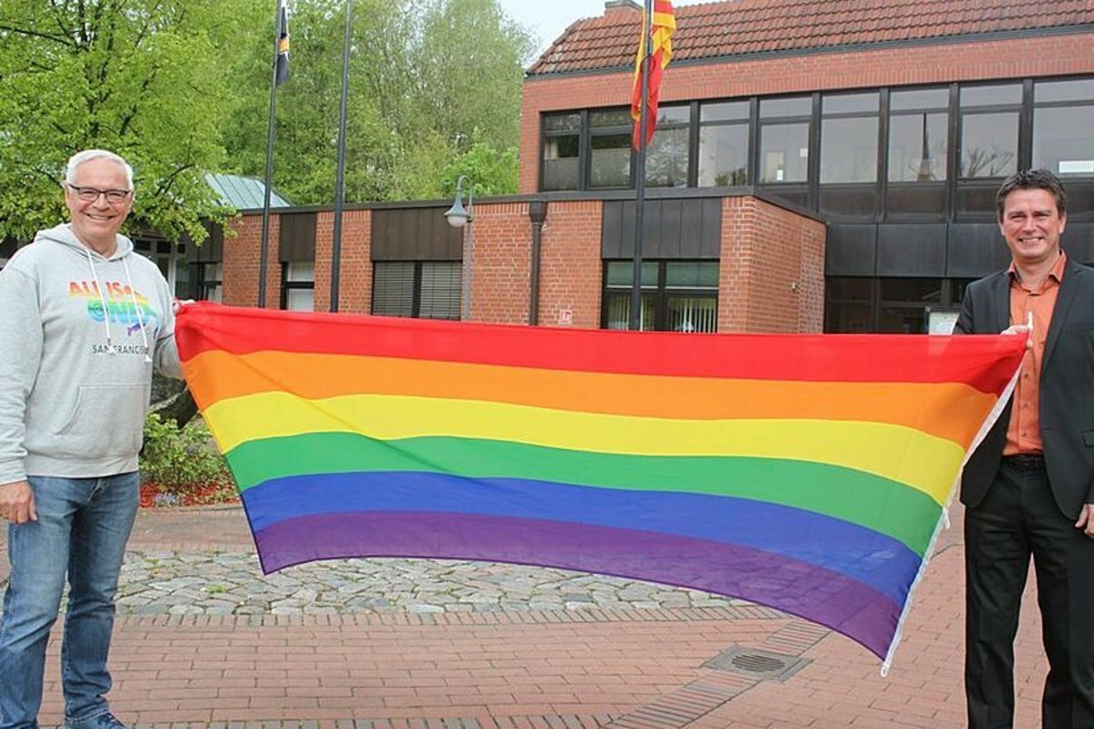 Gemeindevertreter Jens Puschmann und Amtsvorsteher Michael Robien präsentieren eine Flagge vor dem Rathaus